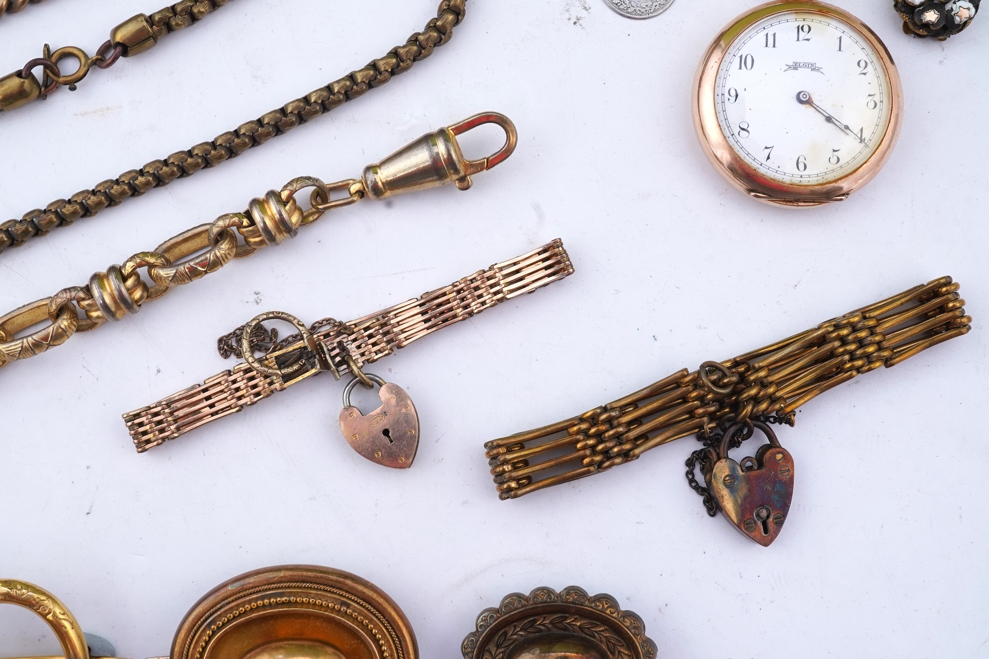 A group of gilt metal/pinchbeck jewels, 19th and early 20th century, comprising: a brooch of knotted design; two gate bracelets; a fancy link bracelet; an open-faced pocket watch; two oval panel brooches, and two watch c
